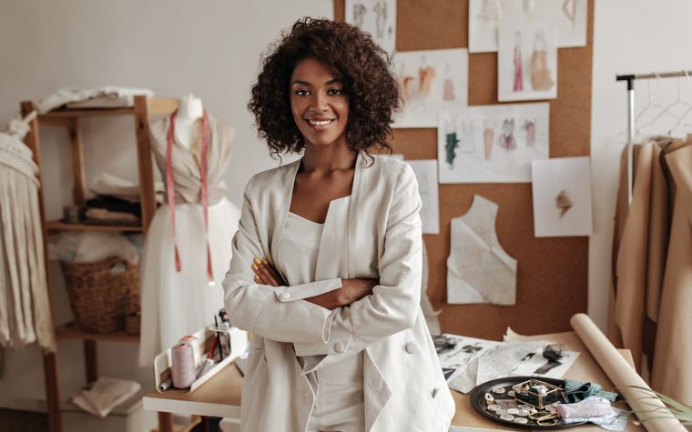 Smiling small-business founder standing arms crossed in her design studio